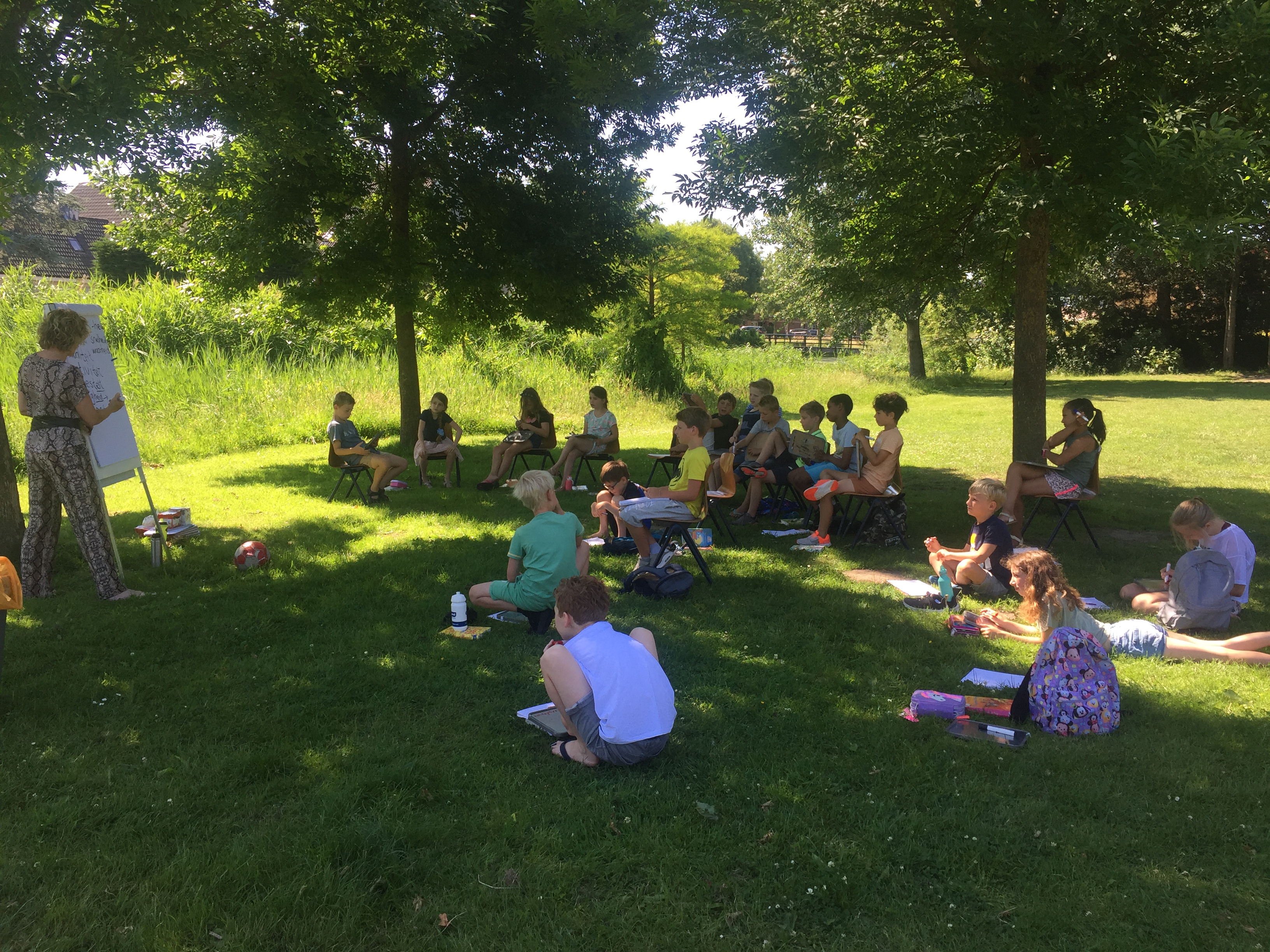 Groep 5-6 doet spelling onder de bomen